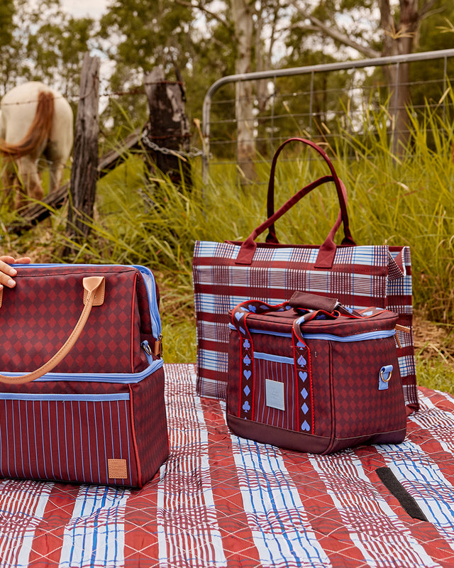 Plaid-patterned bags on a picnic blanket with a horse in the background
