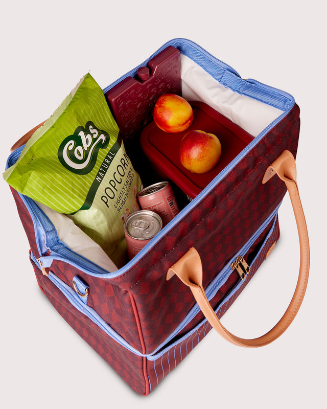 Insulated lunch bag with popcorn, drinks, and fruit on a white background