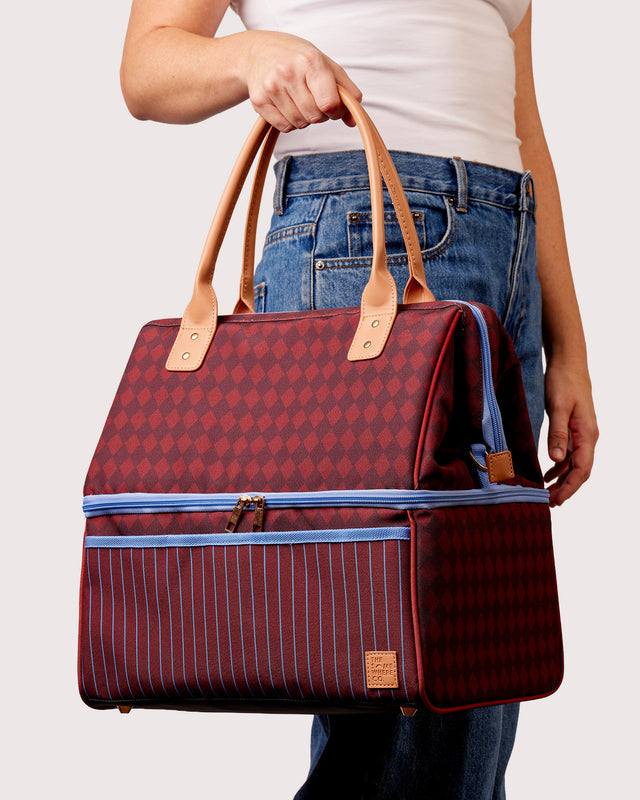Person holding a red patterned bag with blue accents on a white background