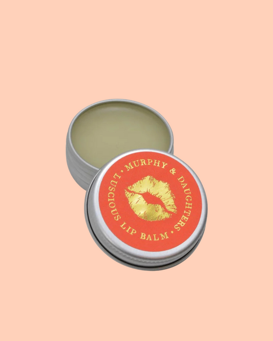 Lip balm tin Murphy and Daughters branding with red label and gold text on a peach background.