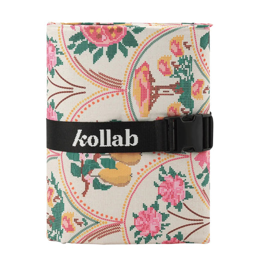 A square picnic mat with a cream background and a colorful floral pattern, secured with a black strap featuring the white 'kollab' logo.
