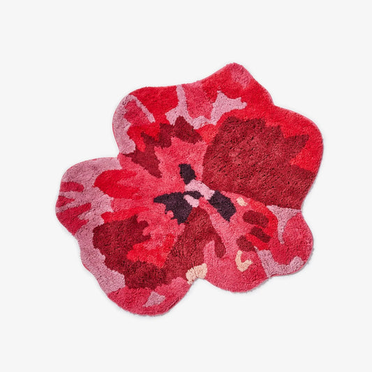 Floral-patterned bath mat with red and pink colors on a white background