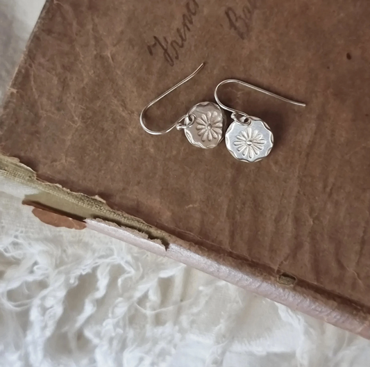 Silver earrings on a textured brown surface