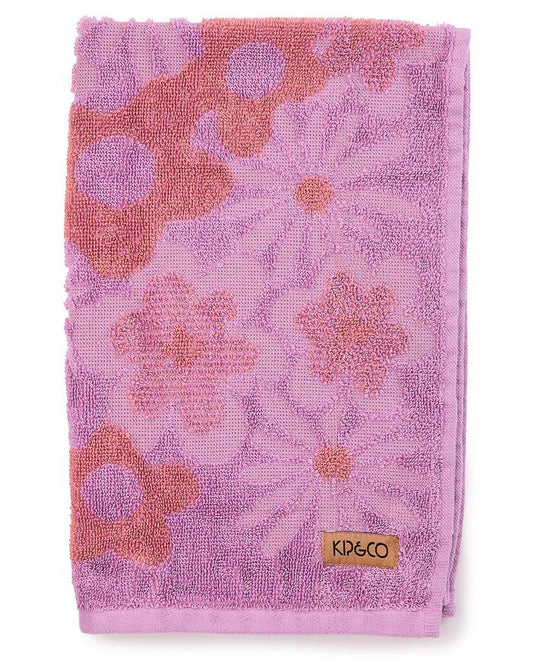 Folded pink towel with floral pattern and Kip & Co label on a white background
