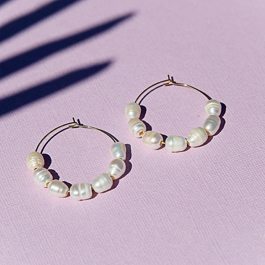 Pearl hoop earrings on a pink background