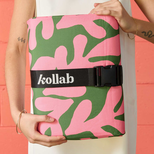Woman holds picnic mat with green and pink pattern.
