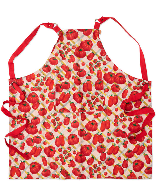 A kitchen apron with a red and white pepper and tomato print, featuring red neck and waist ties, displayed flat against a white background.