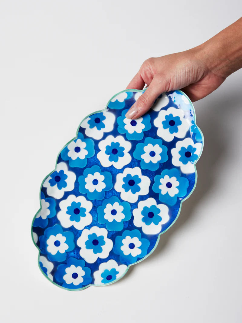 Hand holding a blue and white floral-patterned tray against a white background