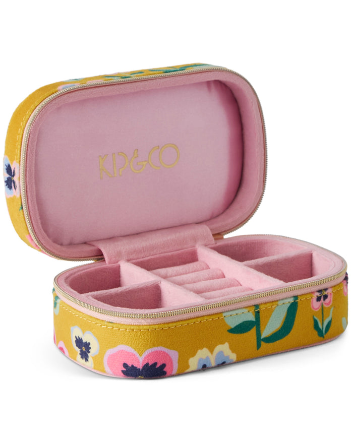 An open KIP&Co jewelry organizer case with a mustard yellow floral exterior and a pink velvet interior, featuring gold lettering on the inside lid.