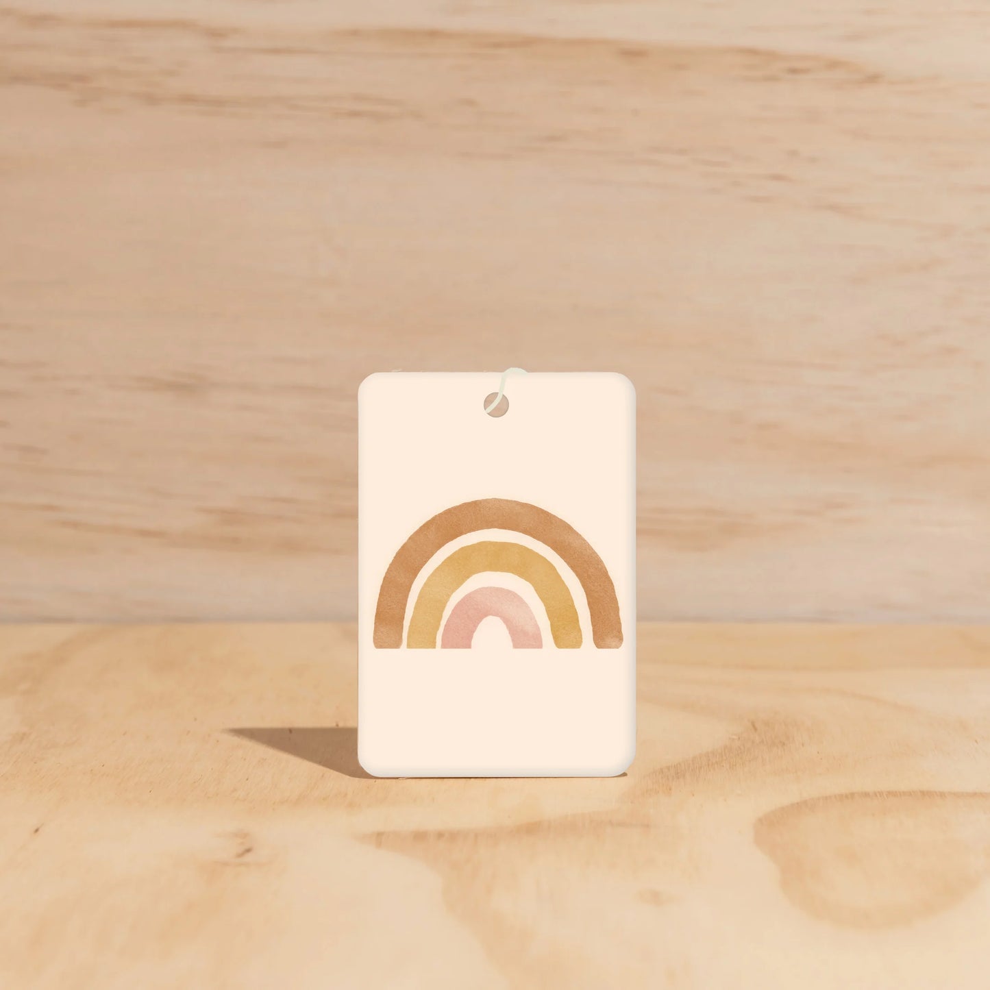 Rectangle car freshener white background with brown, mustard and pink rainbow. 