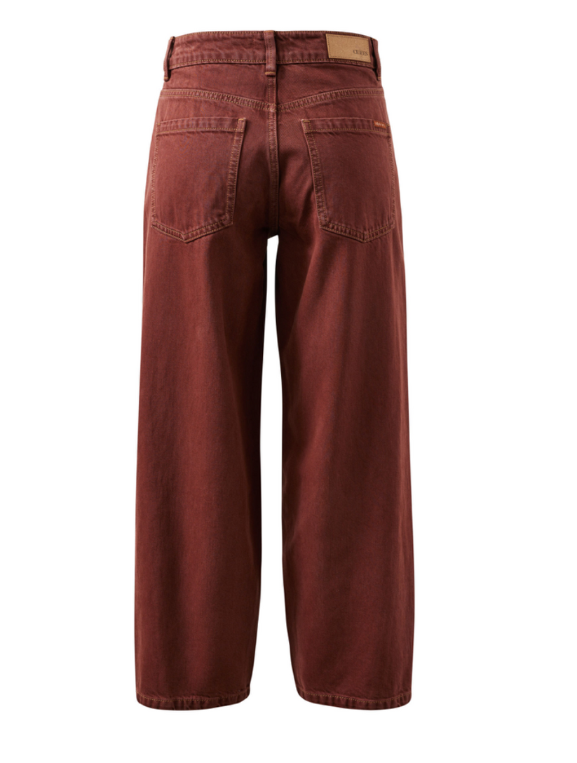 Rust red wide-leg jeans shown from the back, featuring a classic five-pocket design and a tan leather patch on the back waistband, set against a plain white background.