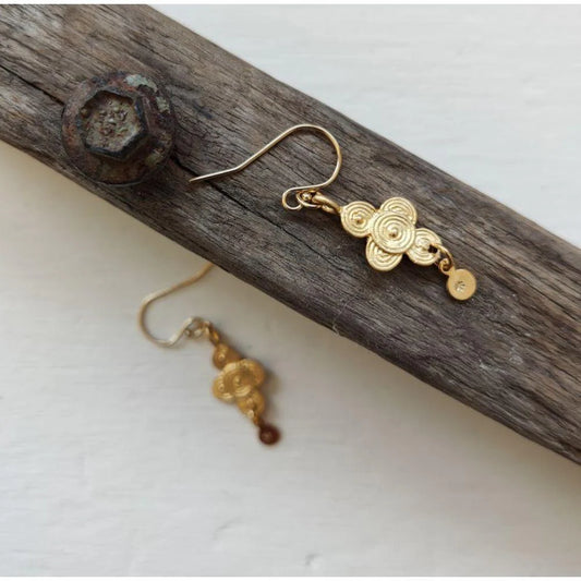 Four point detailed earring, ear wire post and small circle dangling from bottom of earring, captured with one earring sat on natural timber surface and second earring on white background out of focus.