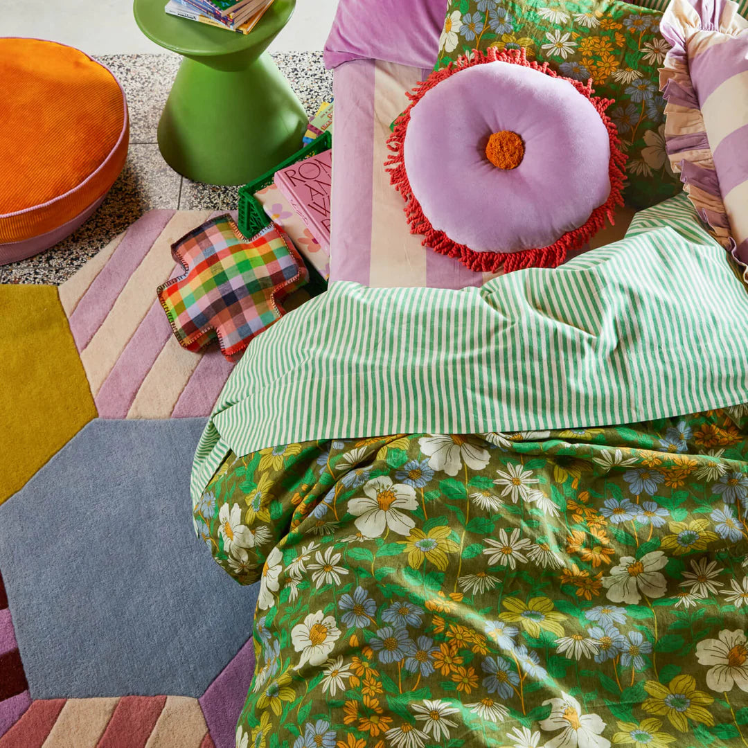 Colorful bedding and pillows on a bed with a geometric floor.