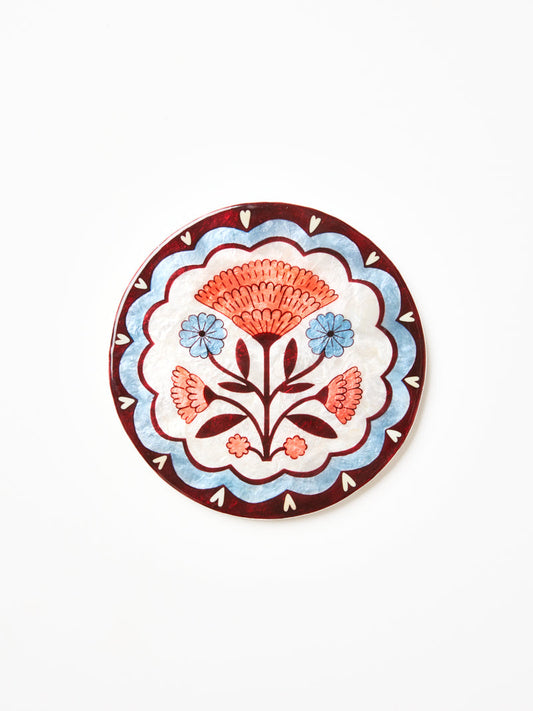 Circle shape wall art with pink and blue flowers and burgundy blue scallop pattern. 
