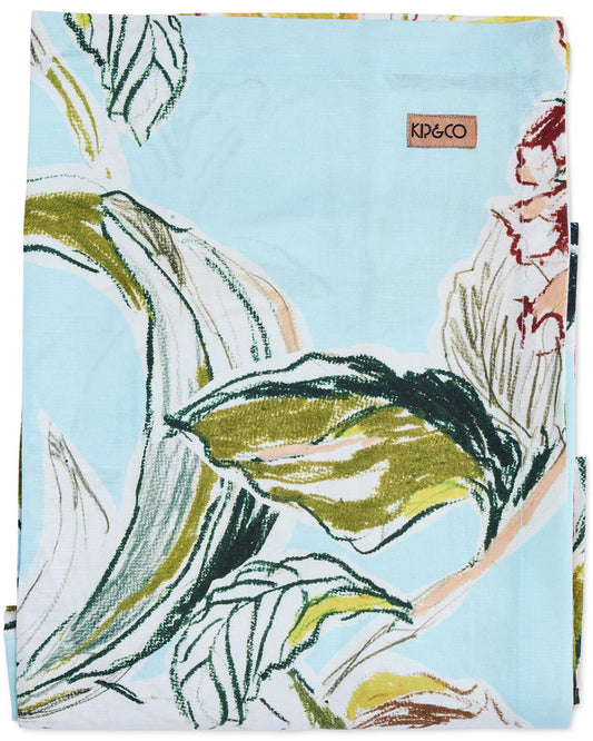 A square fabric item, likely a scarf or small towel, featuring a light blue background with a stylized botanical print in olive green, white, and dark navy outlines. A small brown leather brand tag reading 'KDEGO' is visible near the top right.