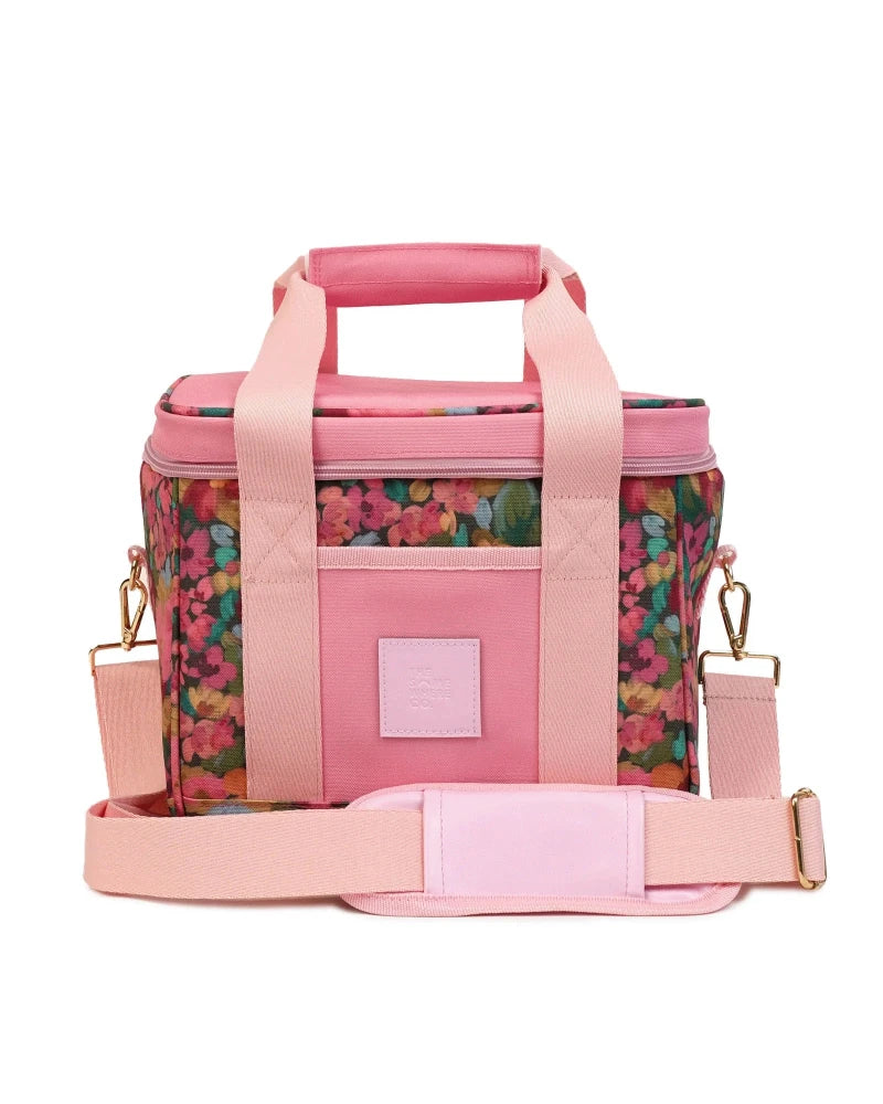 A pink cooler bag with a floral print pattern on the sides, featuring solid pink handles, a front pocket, and an adjustable shoulder strap, shown on a white background.