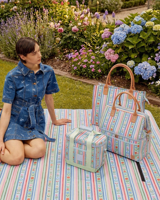 Woman in a garden with striped bags and a box on a colorful blanket