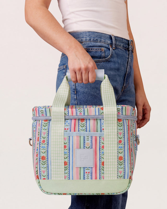 Person holding a colorful patterned bag against a plain background