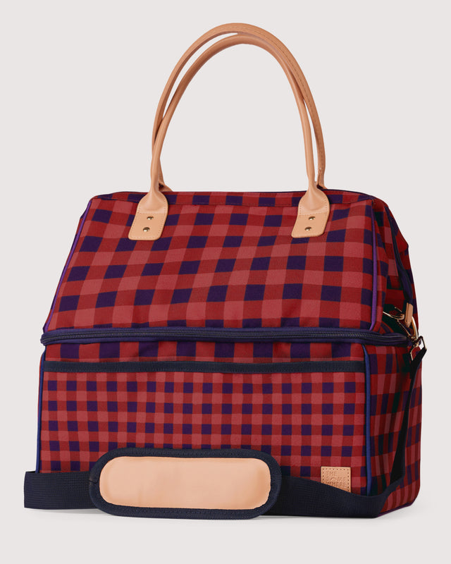 Red and blue checkered bag with brown handles and trim on a light gray background