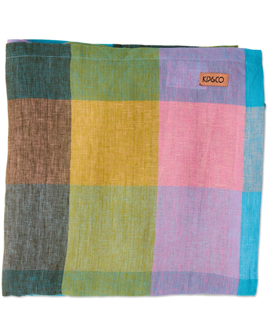 A square woven scarf or shawl from KIP&CO, featuring a large checkered pattern in multiple colors including green, yellow, pink, purple, blue, and brown on a white background.