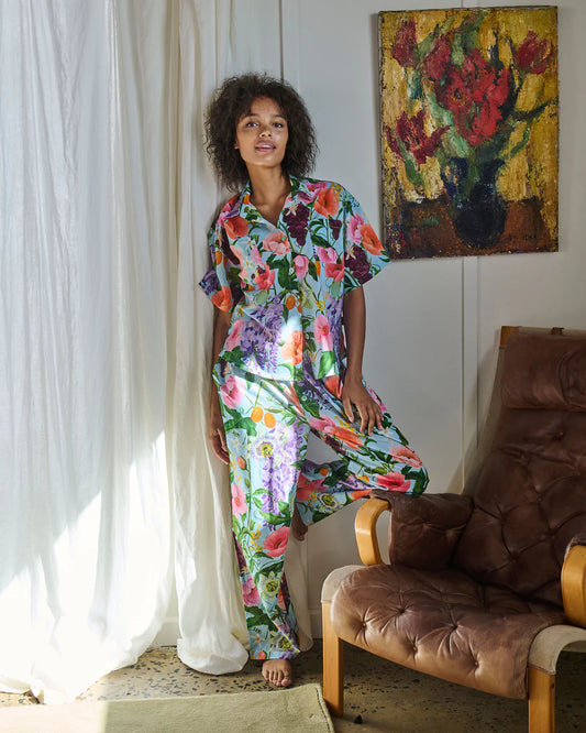 Woman in a colorful floral dress standing in a room with a painting on the wall.