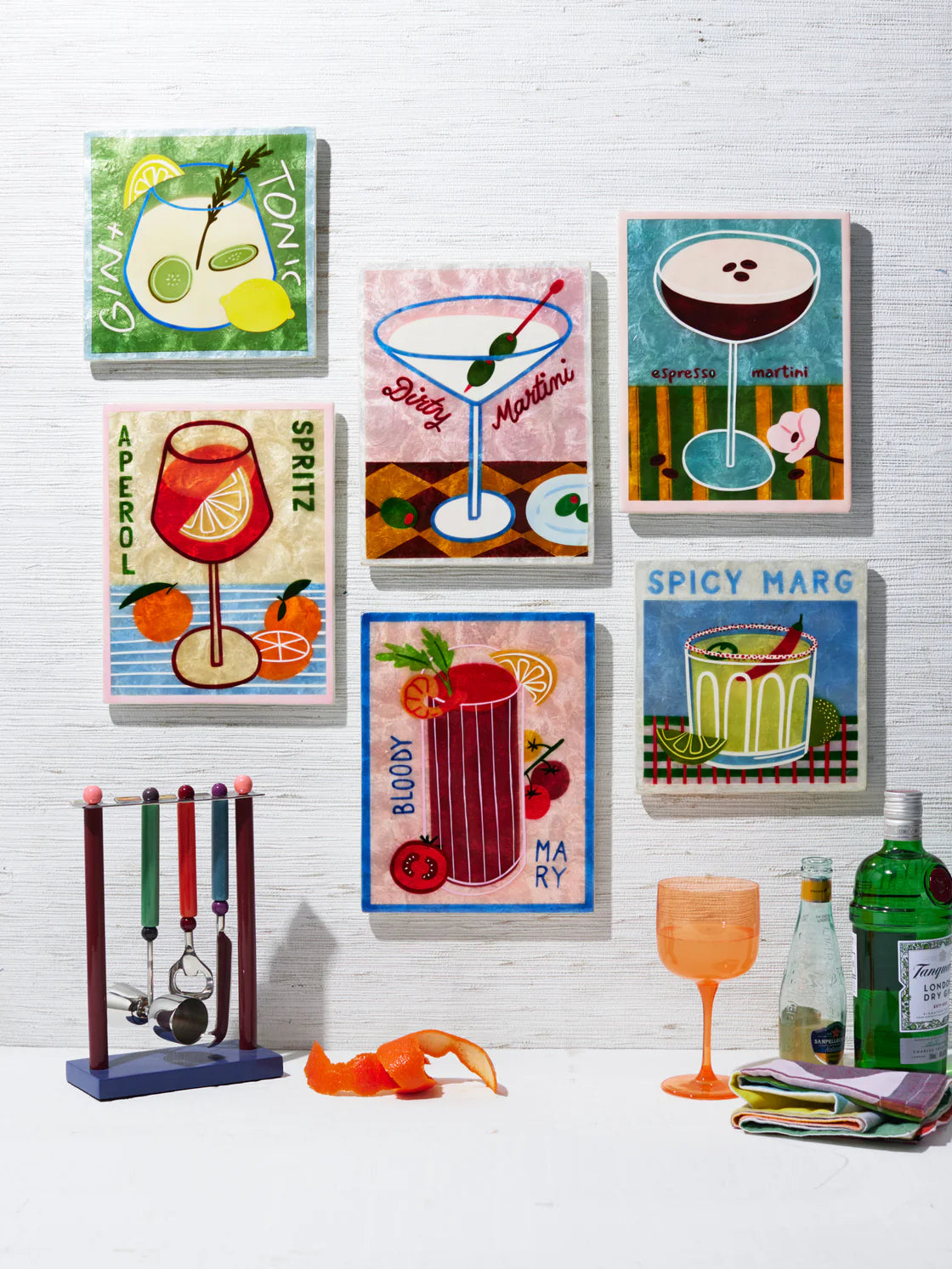 Set of colorful cocktail-themed wall art on a white brick wall.