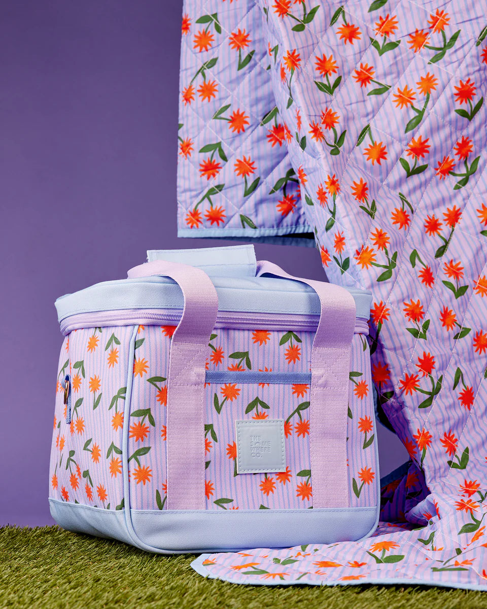 Floral-patterned cooler bag with matching blanket on a purple background