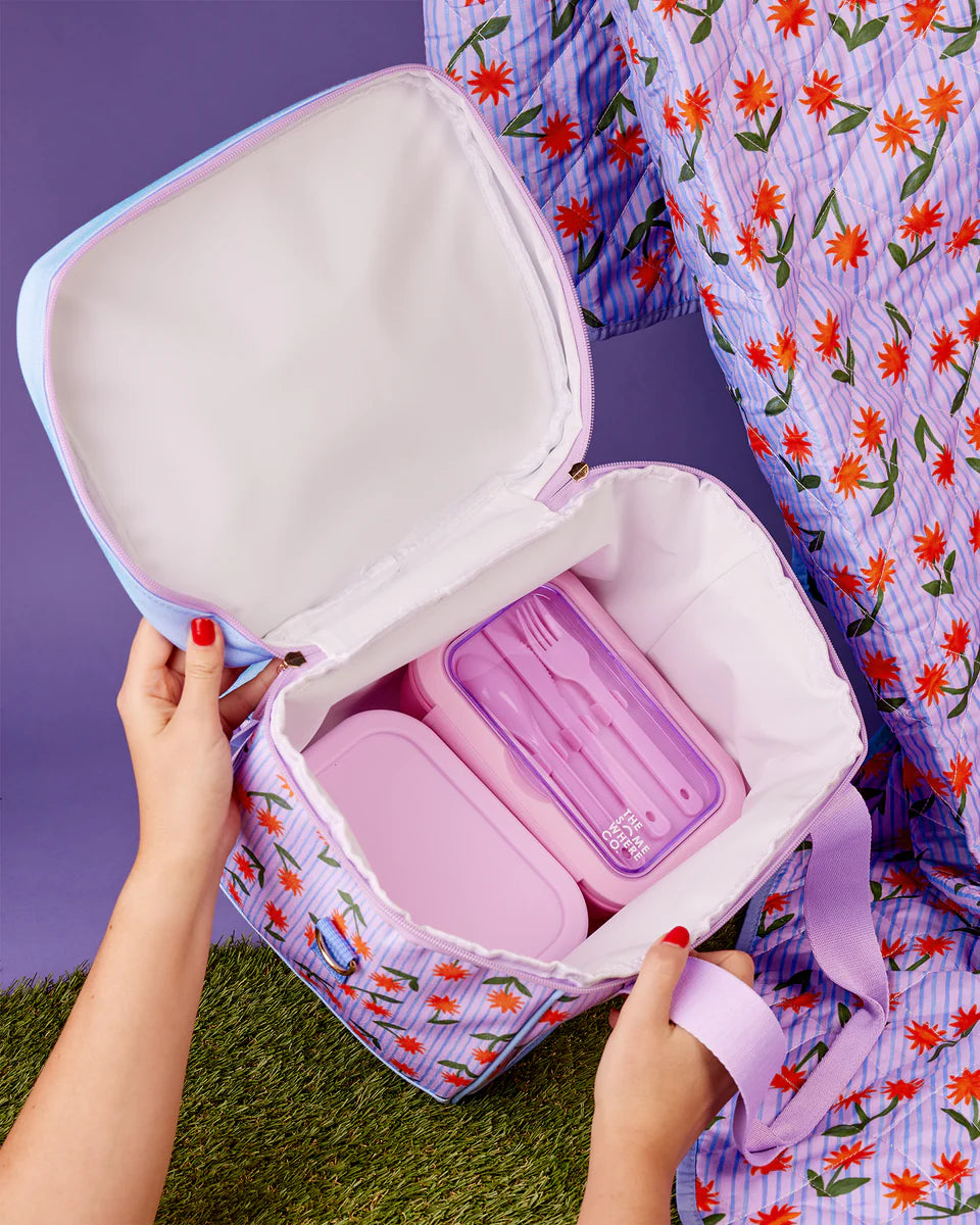Open pink makeup bag with compartments on a floral-patterned fabric background