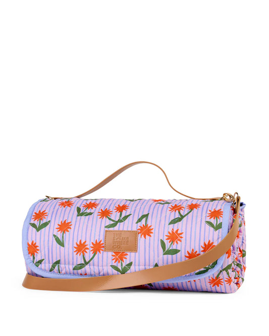 Floral-patterned picnic rug with a brown strap on a white background