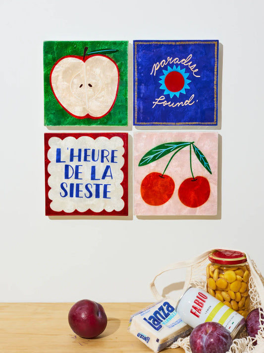 Four colorful tiles with fruit and text on a white background, with snacks on a wooden surface below.