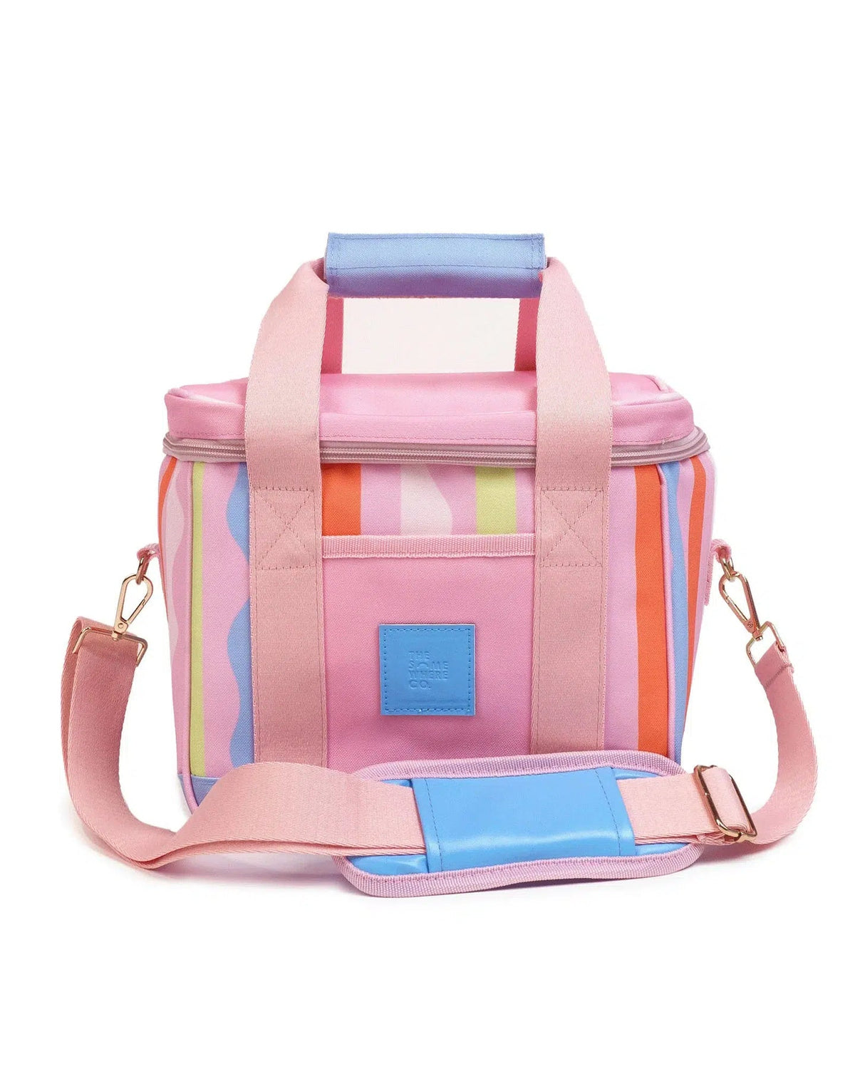 A pastel pink cooler bag with colorful vertical stripes in orange, yellow, and blue on the sides, pink handles and strap, and a small blue brand patch on the front pocket.