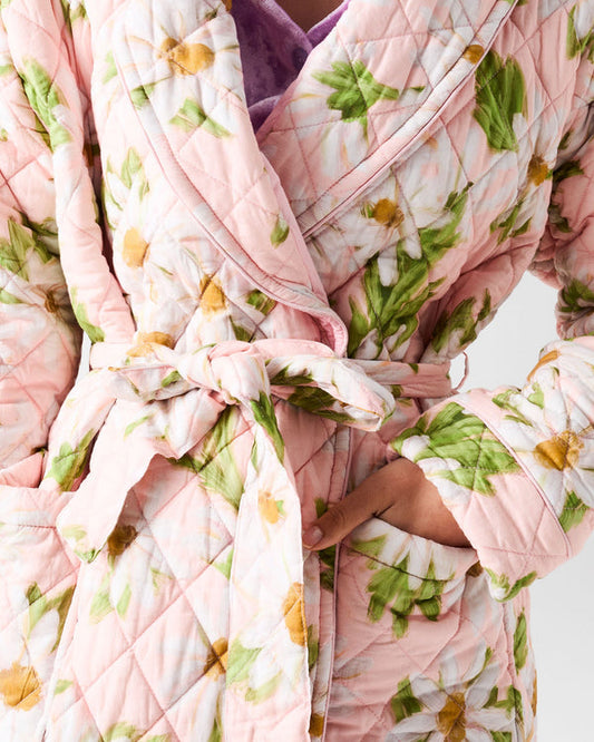 Person wrapped in a floral-patterned quilt with a pink robe.