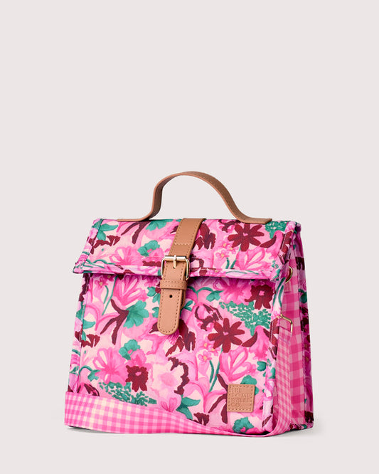 A pink floral insulated bag with a top handle, featuring a pink and green floral print, a brown leather strap and buckle, and a pink gingham check pattern on the base.