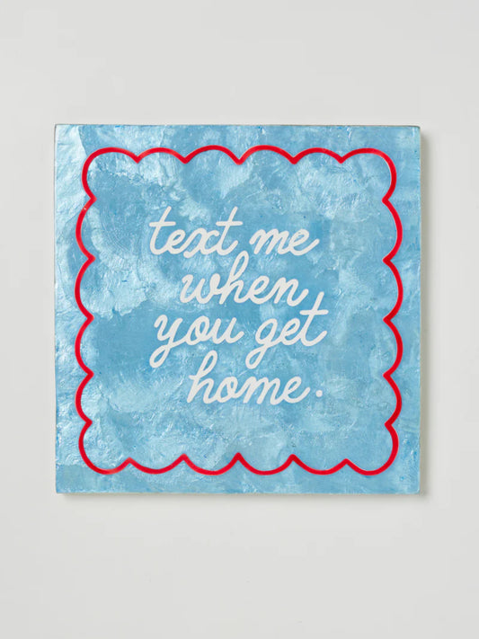 Blue textured tile with red scalloped thin border and white text 'text me when you get home' on a light gray background