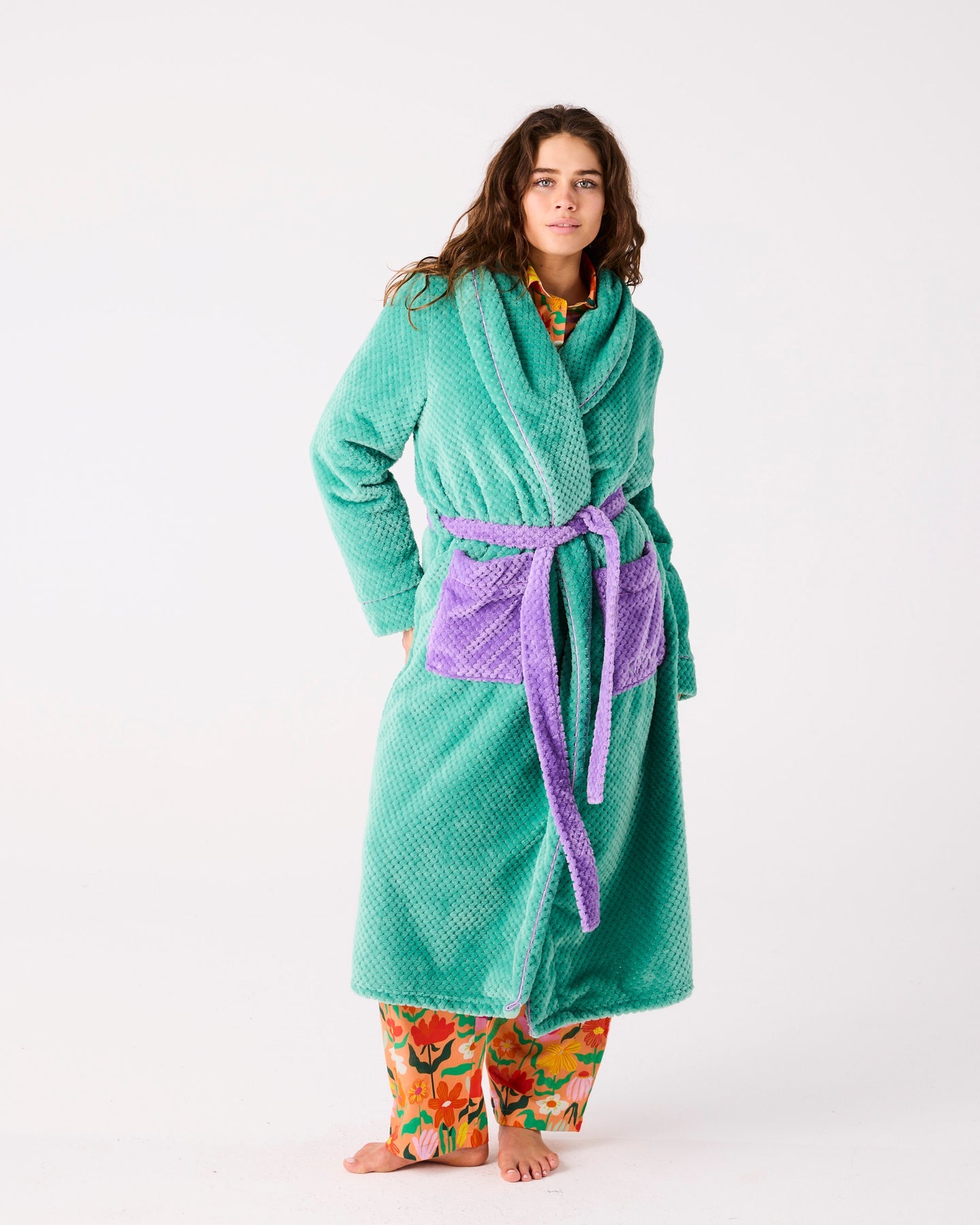 Person wearing a teal robe with a purple belt on a white background