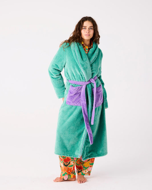 Person wearing a teal robe with a purple belt on a white background