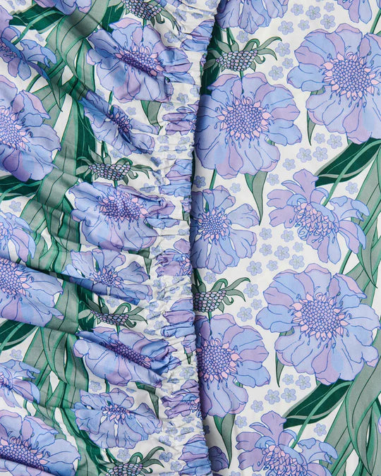 Close-up view of a fitted sheet with a floral pattern featuring lavender purple flowers on a white background.