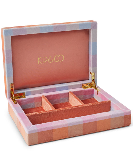 A small jewellery box with a pink, purple, blue and orange check tartan print, opened to show four compartments inside. The brand 'KIP & CO' is visible on the inside lid.