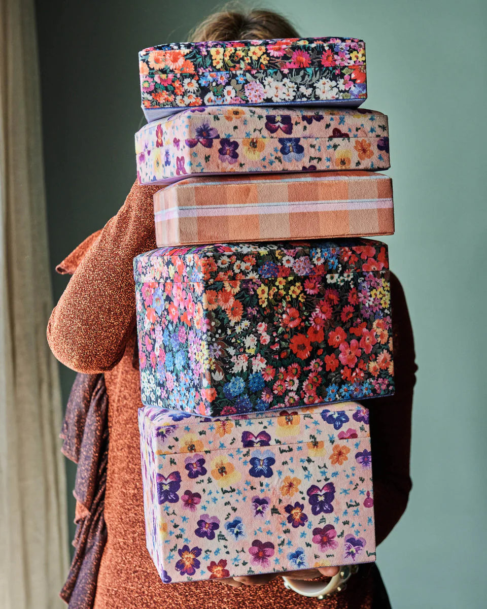 Velvet jewellery boxes stacked and held by woman.