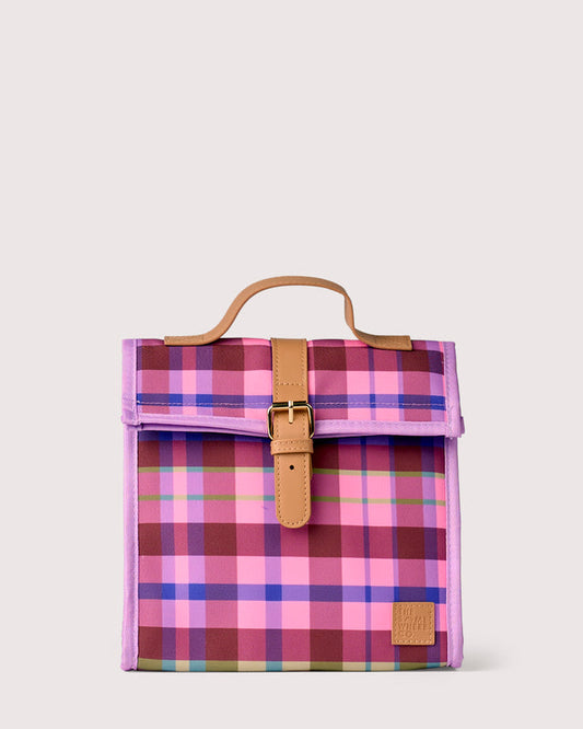 A square canvas bag with a pink, purple, and blue plaid pattern, featuring tan leather trim, a top handle, and a front flap with a buckle closure.