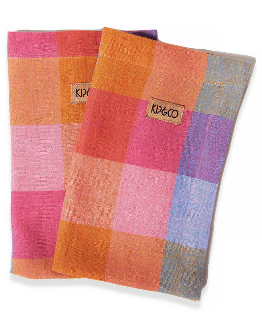 A set of four linen napkins with a pink, purple, blue, and orange check tartan pattern.